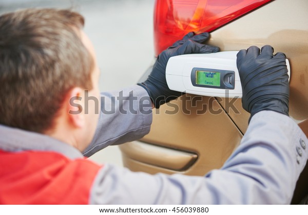 colourist man selecting color of car with paint\
matching scanner