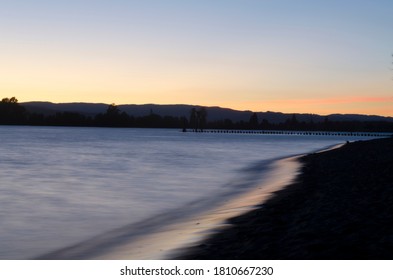 Columbia River Shoreline With Background Hills And Pile Dikes At Sunset