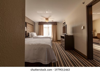 Columbus, OH, 05-19-2021: A Family Suite Hotel Room With Two Queen Size Beds, Carpeted Floors And A Separete Livingroom Area. A Flatscreen Television Is Placed On Top Of A TV Stand With Drawers.