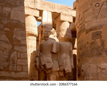 Column hall with Egyptian statues in the Karnak Temple. The columns are decorated with hieroglyphs and ancient symbols. Luxor, Egypt. - Shutterstock ID 2086377166