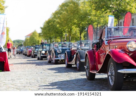 A column of retro cars driving along a cobbled street