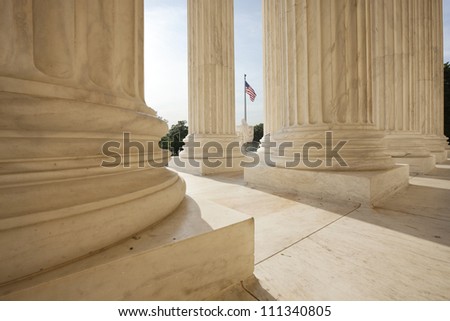 Columns of the Supreme Court building in Washington DC frame an American flag