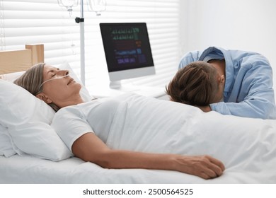 Coma patient. Sad young man near his unconscious mother in hospital - Powered by Shutterstock