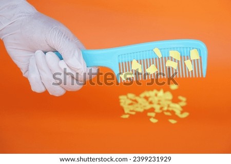 Comb and small pieces of paper. Equipment, prepared to do experiment about static electricity. Orange background. Concept, Science lesson, fun and easy experiment. Education. Teaching aids.  