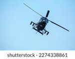 Combat helicopter is flying against isolated blue sky. Combat helicopter attack enemy.