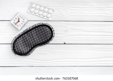 Combat Insomnia. Sleeping Pills Near Sleep Mask And Alarm Clock On White Wooden Background Top View Copyspace