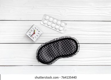 Combat Insomnia. Sleeping Pills Near Sleep Mask And Alarm Clock On White Wooden Background Top View