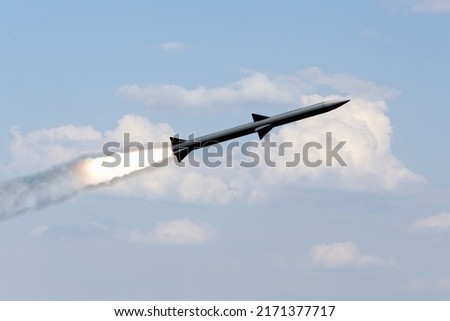 A combat rocket is flying above the clouds, smoke and fire from the rocket. Concept: missile attack, air attack, war between Russia and Ukraine.