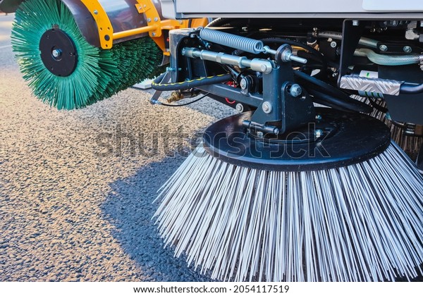 Combination of two sweeping brushes\
of municipal street sweeper machine close up. Year-round urban\
street cleaning concept. Modern street sweeping\
equipment.