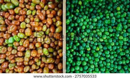 combination two vegetables on the same basket, tomatoes cherry and green lime. they separate with the wooden border, exact in the middle