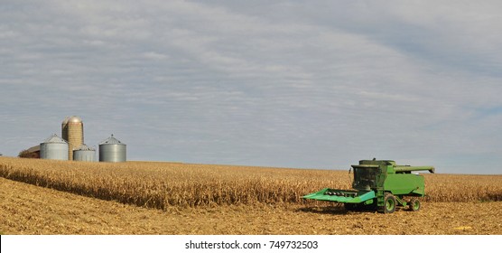 Combine in corn field with grain bins in the background