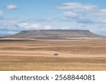 A Combine harvester drive in front of the Square Butte in Montana, Usa