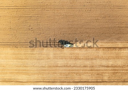 Similar – A combine harvester is harvesting grain crops on a cornfield in the evening sun seen from above