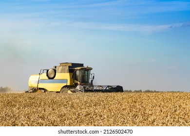 Combine Harvester Harvests Ripe Wheat. Ripe Ears Of Gold Field On The Sunset Cloudy Orange Sky Background. . Concept Of A Rich Harvest. Agriculture Image