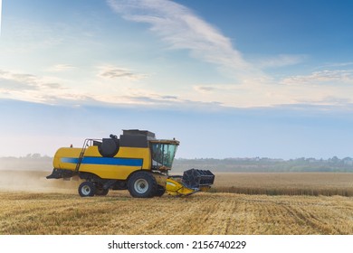 Combine Harvester Harvests Ripe Wheat. Ripe Ears Of Gold Field On The Sunset Cloudy Orange Sky Background. . Concept Of A Rich Harvest. Agriculture Image