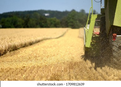 Combine Harvester On Grain Field In The Salzkammergut (Upper Austria, Austria). A Combine Harvester Is Used To Harvest The Winter Barley.