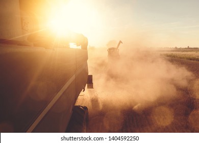 A Combine harvester and a tractor harvesting wheat during sunset - Shutterstock ID 1404592250