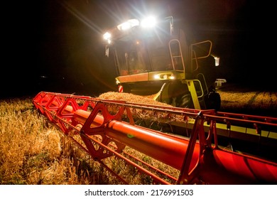 Combine Harvester Working In Wheat Field At Dark Night. Agriculture Background. Harvest Season