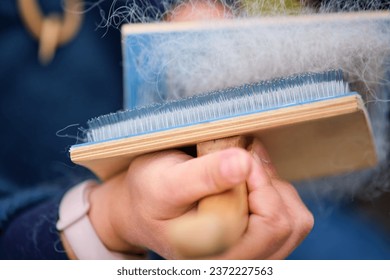 Combing animal hair with a brush for spinning woolen clothes - Powered by Shutterstock