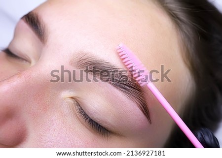 combing the hairs in the eyebrows with a brush after the procedure of coloring and laminating the eyebrows ストックフォト © 
