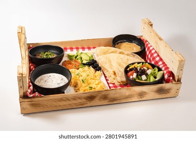 Combo breakfast set with scrambled eggs salmon and flatbread in wooden crate.
