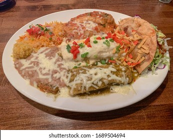 A combo plate with chile relleno, crispy taco, enchilada, tamale, rice and refried beans. Mexican food.