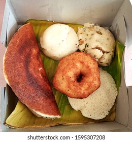 Combo South Indian Vegetarian  Breakfast Packed In A Take Away Box In Bengaluru. Neatly Packed On Banana Leaf To Keep Food Fresh And Healthy. Idly, Masala Dosa, Vada ,sweet And Upma Food In The Box.