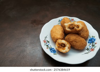 Combro, a traditional snack from West Java, Indonesia, on white plate,  made from grated cassava which is shaped round or oval and filled with oncom and chili sauce and then fried.