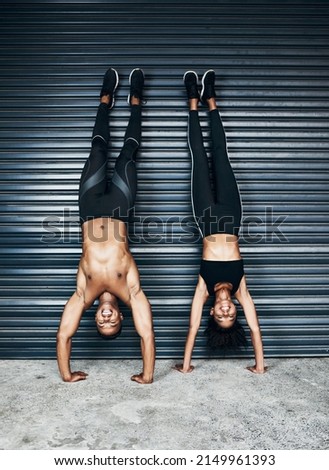 Come hang with us. Shot of a sporty young couple doing handstands against a grey background.