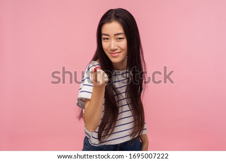 Come here! Portrait of attractive girl with brunette hair in striped t-shirt gesturing come to me, beckoning with finger, inviting for confidential talk. indoor studio shot isolated on pink background Stock photo © 