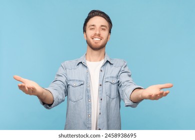 Come into my arms. Portrait of unshaven man reaching out to camera, stretching arms to hug you, looking at camera with toothy smile, wearing denim shirt. Indoor shot isolated on blue background. - Powered by Shutterstock