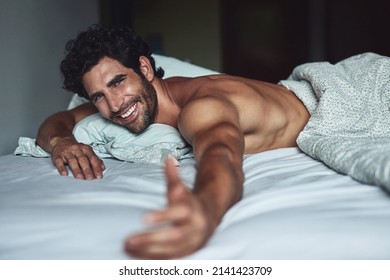Come and join me. Cropped shot of a handsome young shirtless man lying in bed at home.