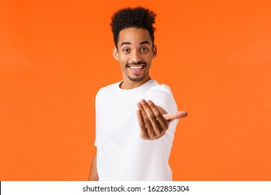 Come on join us. Happy and friendly outgoing african-american modern male student inviting participate, hiring, make come here gesture and smiling, lure, standing orange background