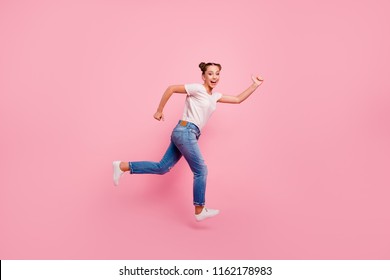 Come on, race! Full legs, body, size portrait of cute and lovely happy brunette girl who runs through the air in a white T-shirt and blue jeans isolated on vivid pink background