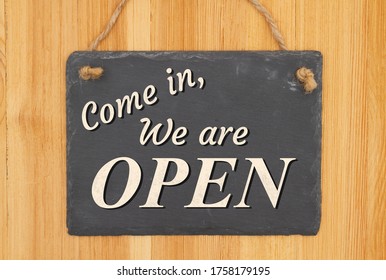 Come In We Are Open Type Message On A Hanging Chalkboard Sign On Wood