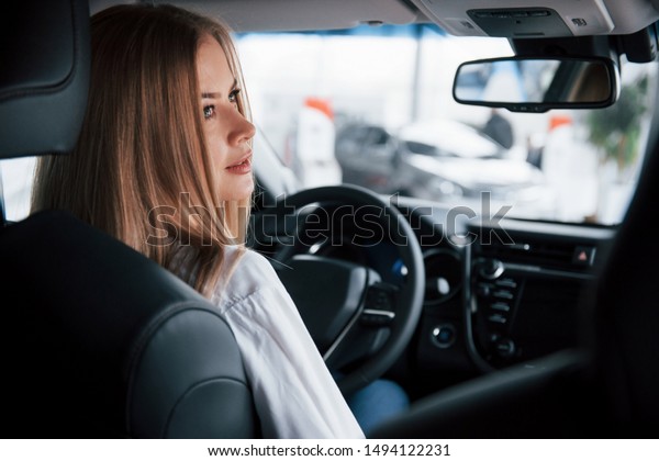 Comfort costs some money.
Beautiful blonde girl sitting in the new car with modern black
interior.