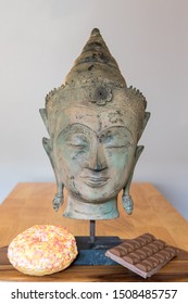 Comfort Food. Mental Health And Wellbeing With Spiritual Buddha Statue, Sweet Doughnut And Chocolate. Representing Mind Over Desire. Self Control In The Face Of Temptation. 