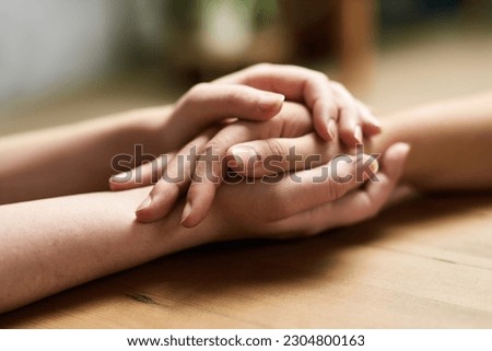 Comfort, holding hands and support of friends, care and empathy together on table after cancer. Kindness, love and women hold hand for hope, trust or prayer, solidarity or compassion, help or unity.