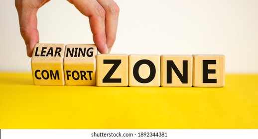 Comfort or learning zone symbol. Hand turns wooden cubes and changes words 'comfort zone' to 'learning zone'. Beautiful yellow table, white background, copy space. Business, psychology concept.