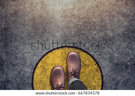 Comfort Zone concept, Male with leather shoes steps over circle line to outside bound, Top view and Dark tone, Grunge Dirty Concrete Floor as Background