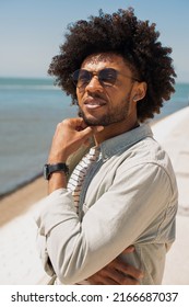 Comfortable African American man walking on embankment. Stylish man in casual clothes having walk on summer day. Relaxation, leisure concept