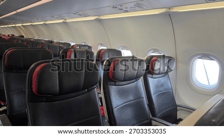 Comfortable airplane interior seating with empty aisle in a modern passenger aircraft cabin.