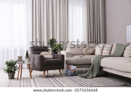 Comfortable armchair and sofa near window in living room. Interior design