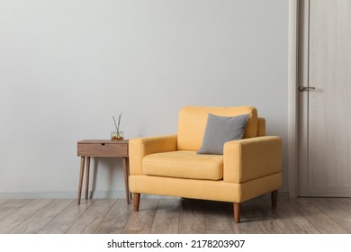 Comfortable Armchair With Table And Air Freshener Near Light Wall In Room