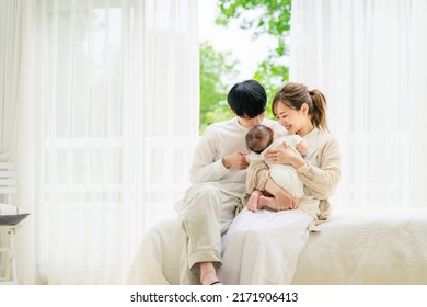 Comfortable Asian Young Couple And A Baby In The House. Child Rearing. Newborn.