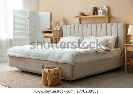 Comfortable bed with clean linens and bedside table in room. Interior design