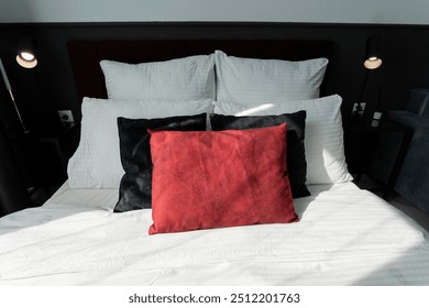 A comfortable bed featuring crisp white sheets accompanied by stylish black and red pillows, creating a pleasant sleeping atmosphere