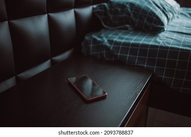 Comfortable Bed And Nightstand With Black Smartphone In Modern Hotel Room Interior