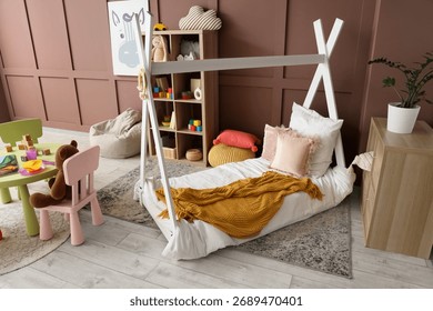 Comfortable bed, shelving unit, table and chairs in interior of children's room