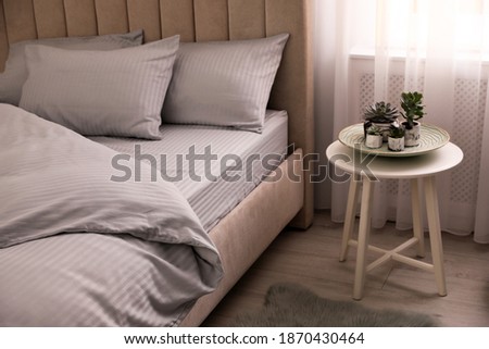 Comfortable bed with soft blanket near window indoors